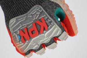 Uma mão fechada em punho utiliza uma luva de EPI de alta performance, essencial para a segurança e proteção contra riscos na operação de mineração. O design robusto do equipamento destaca a importância da manutenção e do monitoramento de integridade física, reforçando a cultura de prevenção e a eficácia do treinamento técnico no uso correto de equipamentos de segurança